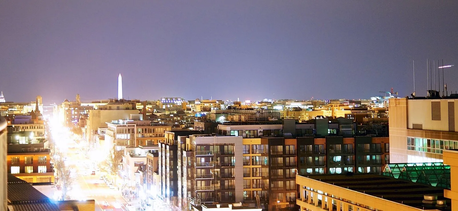 Looking down 14th Street from U Street at night toward the lit Washington Monument, the heart of DC nightlife