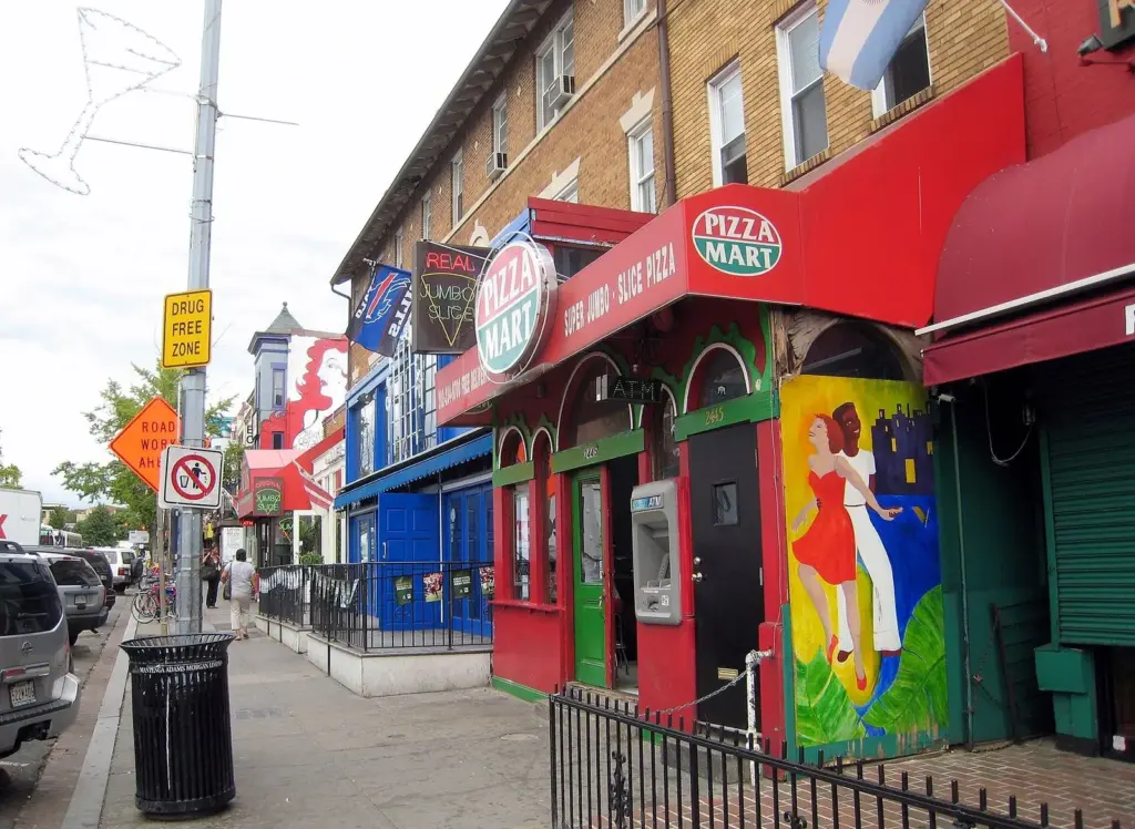 Brightly painted storefronts on 18th Street in Adams Morgan, including a jumbo slice pizza shop