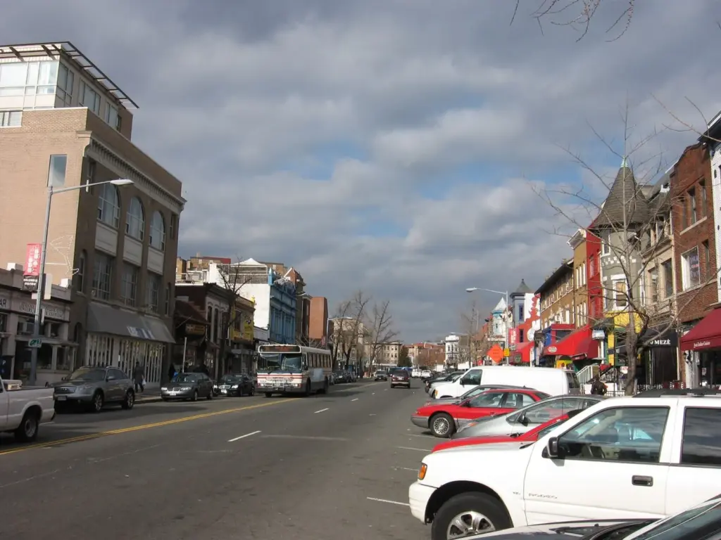 Low-rise shops and restaurants along 18th Street in Adams Morgan under a cloudy sky