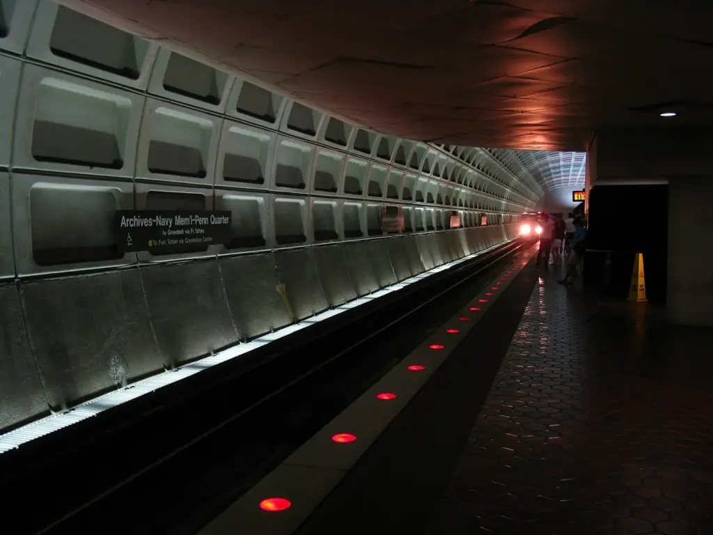 The vaulted concrete platform of Archives-Navy Memorial-Penn Quarter Metro station with a train arriving