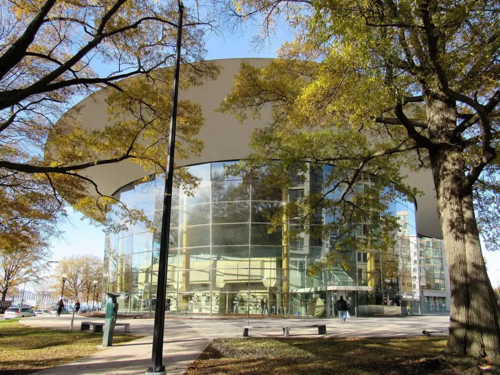 The glass and timber front of Arena Stage's Mead Center under autumn trees