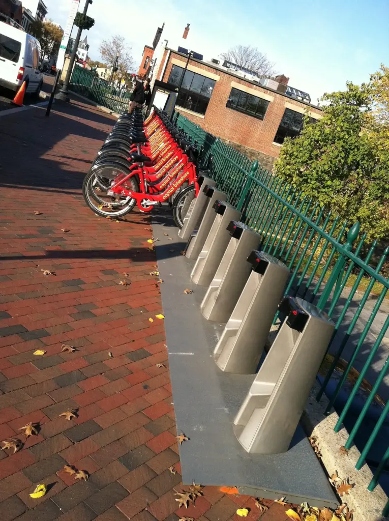 A row of red Capital Bikeshare bikes locked into a docking station on a brick sidewalk