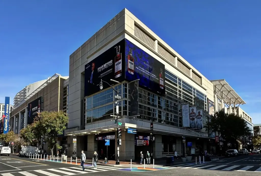 The corner entrance and tall glass facade of Capital One Arena on a sunny day in Chinatown
