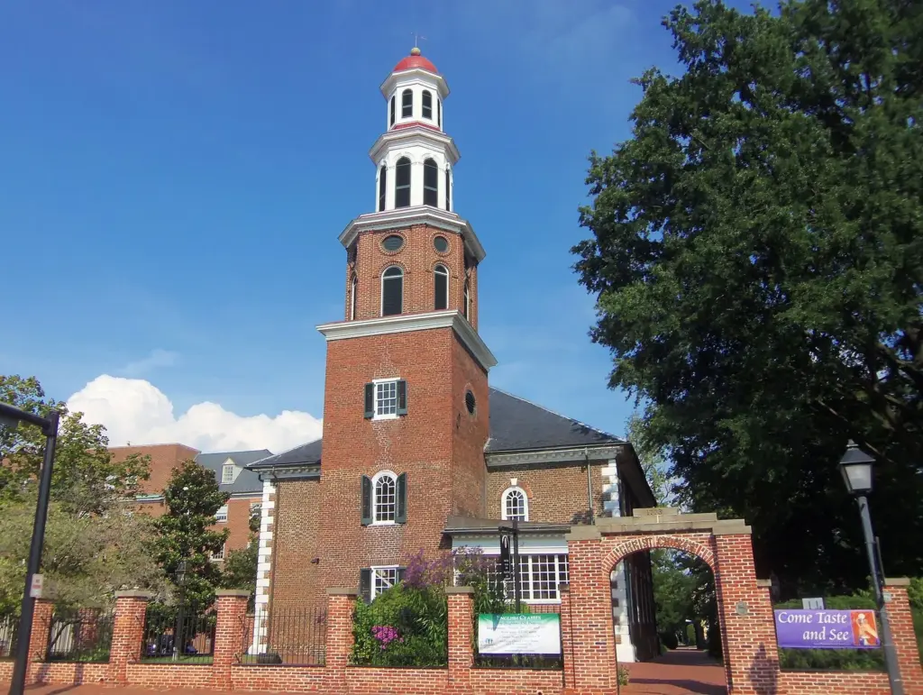 Christ Church's red-brick tower and white cupola behind a brick wall and gate