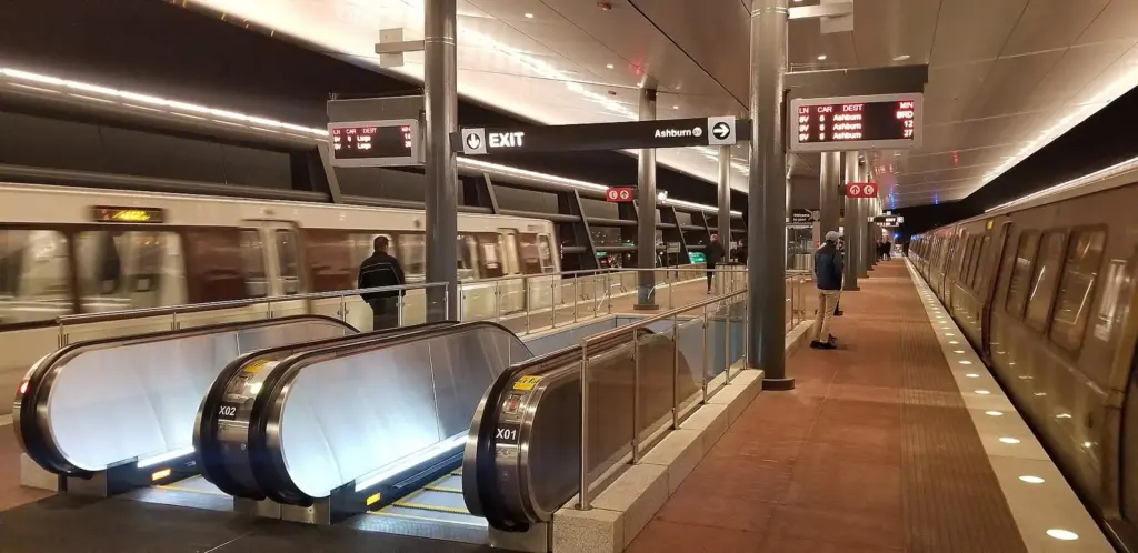Moving walkways beside a waiting Silver line train at the underground Dulles Airport Metro station