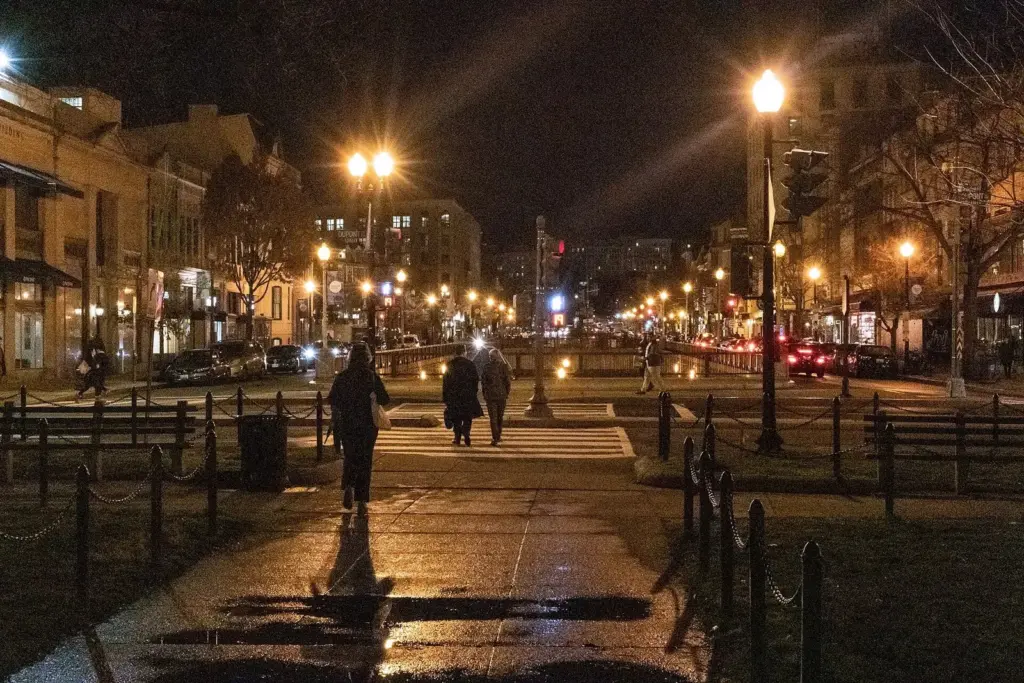 Dupont Circle's park at night, with streetlights along the paths and lit storefronts beyond