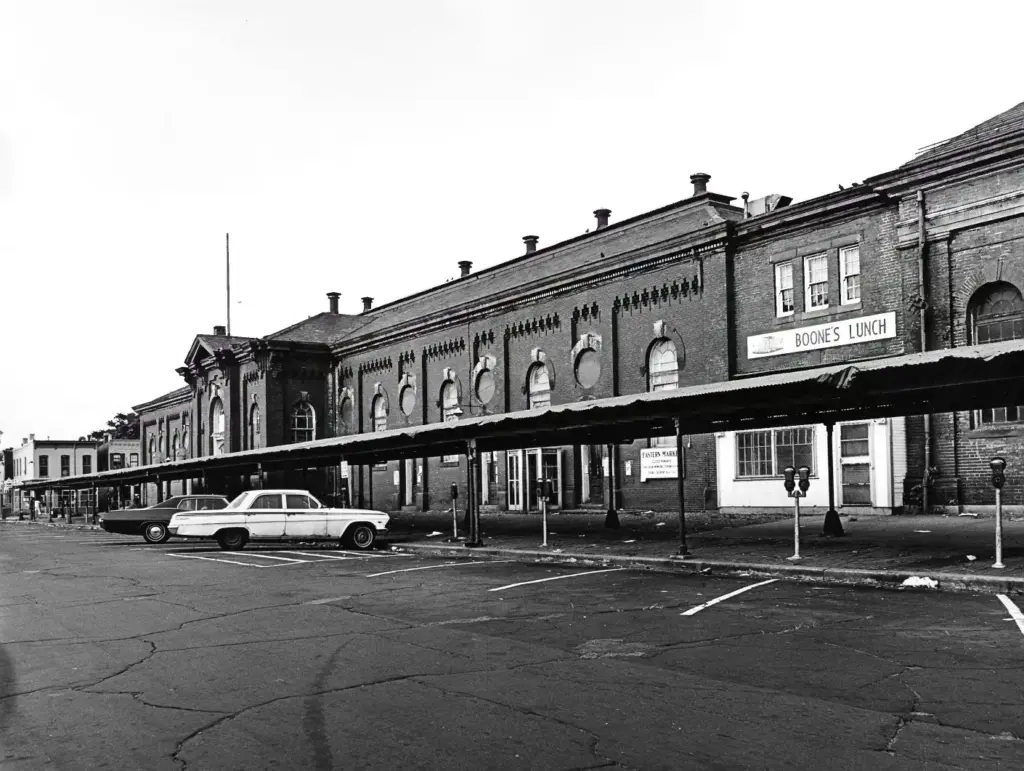 Black-and-white photo of the long brick Eastern Market hall and its covered sidewalk arcade on 7th Street SE