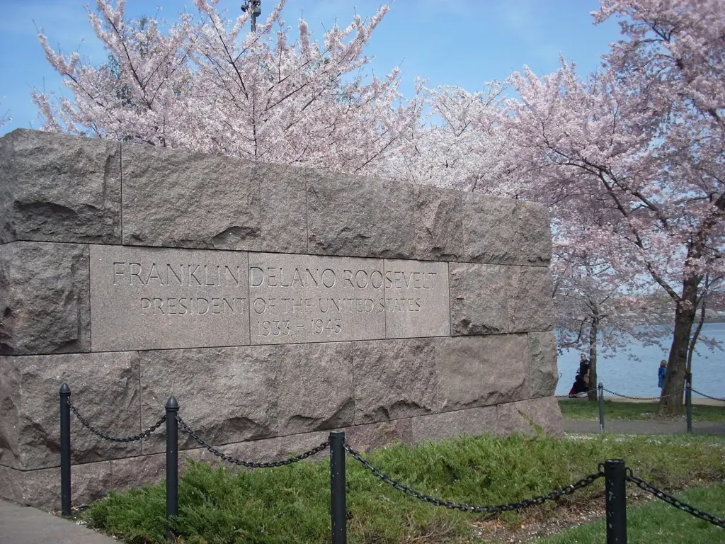 Rough-cut red granite entrance wall of the Franklin Delano Roosevelt Memorial beside flowering cherry trees