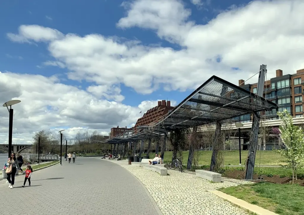 Paved riverside promenade and steel shade canopy in Georgetown Waterfront Park on a sunny day
