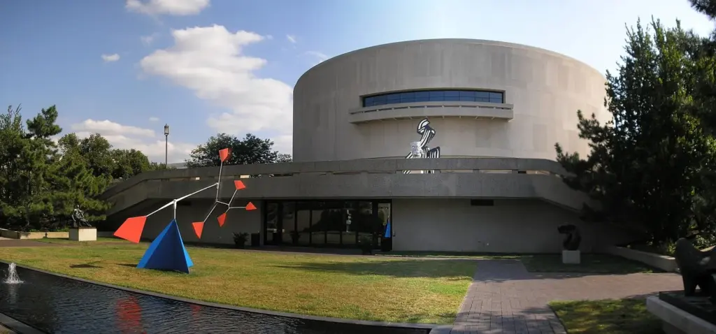 The round concrete Hirshhorn Museum building with a red and blue abstract sculpture on its plaza