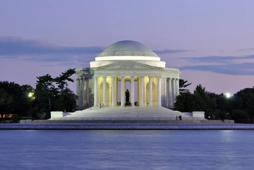 The domed Jefferson Memorial lit at dusk, seen across the water of the Tidal Basin