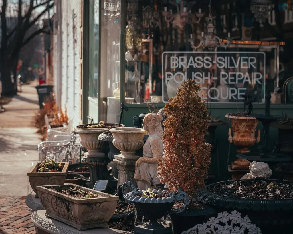 Garden urns, statues and a Brass Silver Polish Repair sign in an Old Town Alexandria antiques shop window on King Street