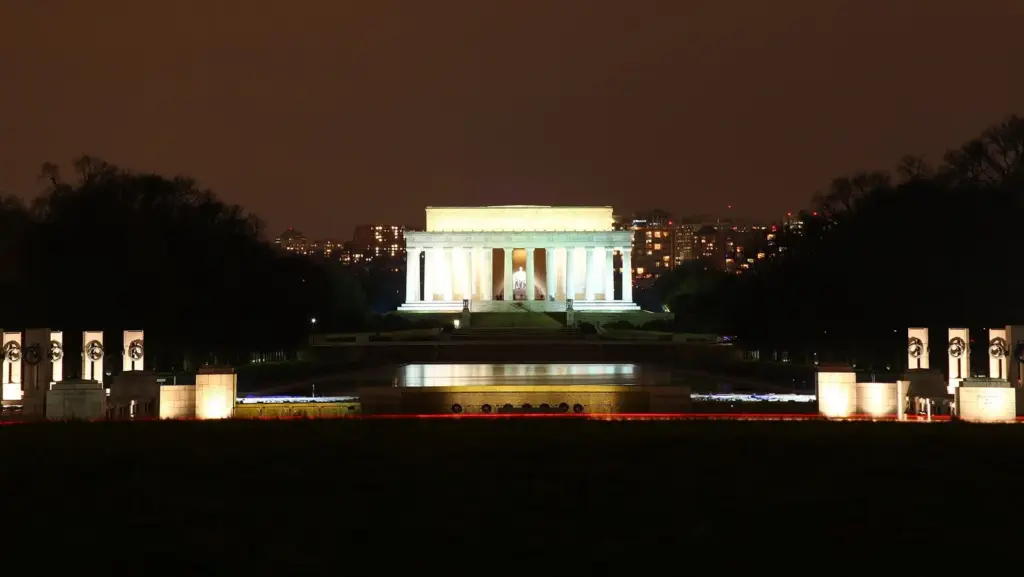 The memorial glowing white at night at the far end of the Reflecting Pool, seen from the east