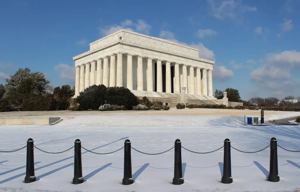 The Lincoln Memorial under blue sky with snow covering the plaza and the chained bollards in front