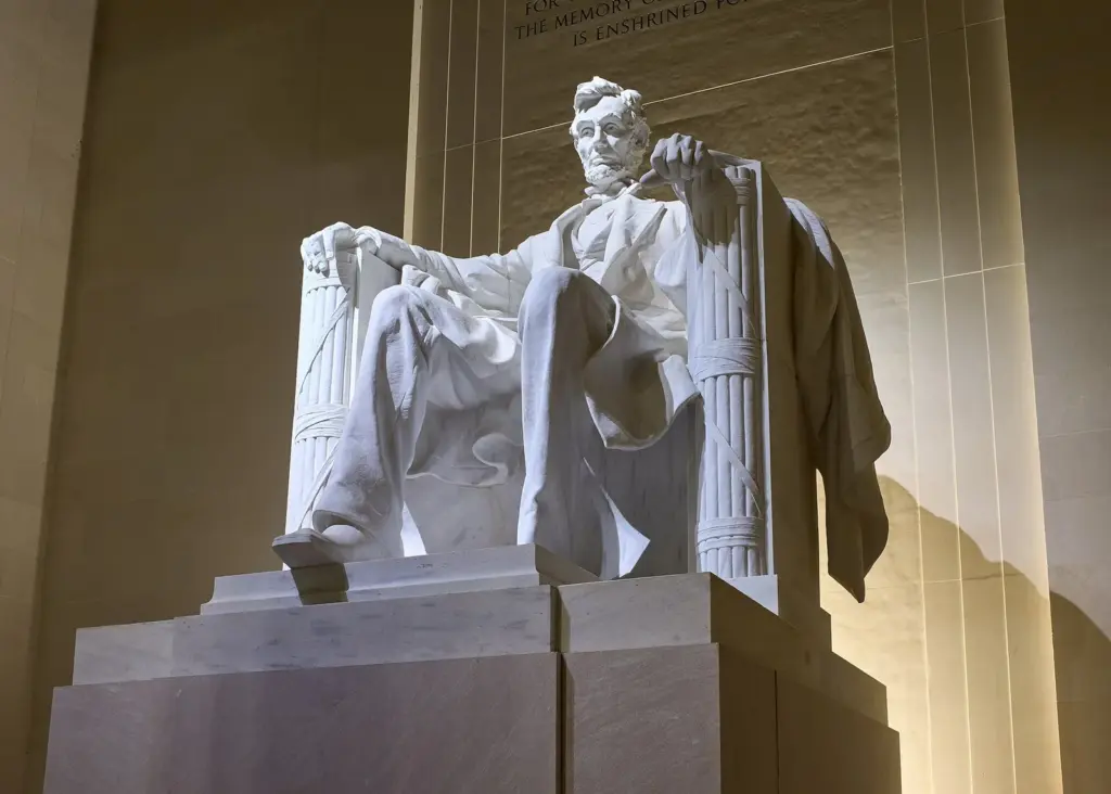 The seated white marble statue of Abraham Lincoln inside the Lincoln Memorial chamber, lit from above