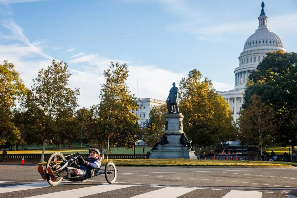 A hand-cycle athlete racing past the Capitol dome and a statue during the Marine Corps Marathon