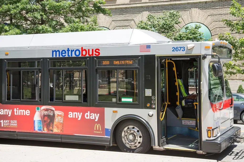 A white and red Metrobus with its doors open at a stop, showing an old route number on its sign