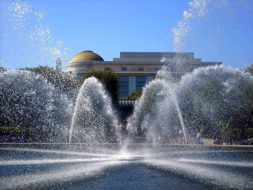 Arcs of water from the fountain in the National Gallery of Art Sculpture Garden, with the Natural History museum dome behind