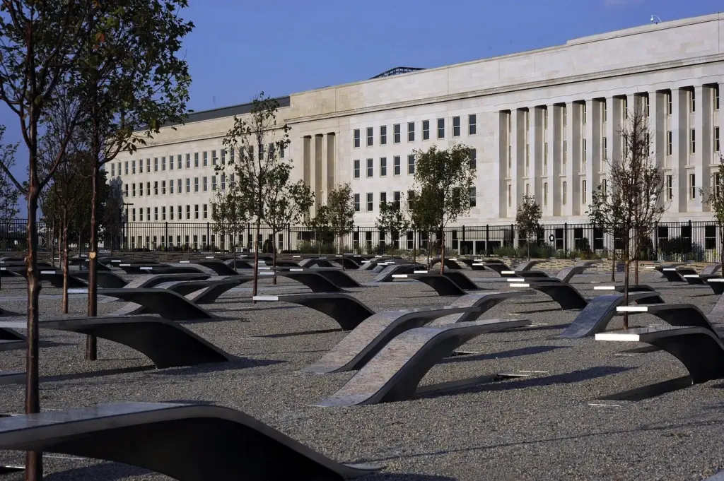 Rows of cantilevered steel benches at the Pentagon Memorial beside the Pentagon's facade