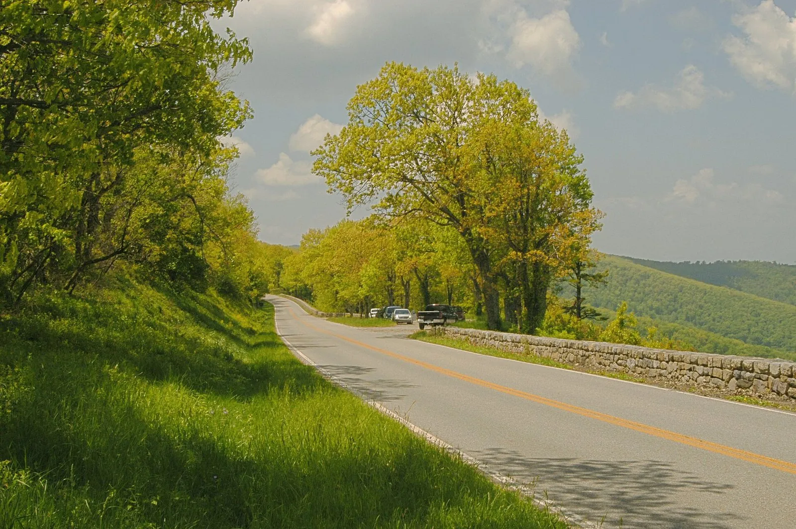 Skyline Drive curving past a stone wall and spring trees in Shenandoah National Park, one of the best day trips from DC by car