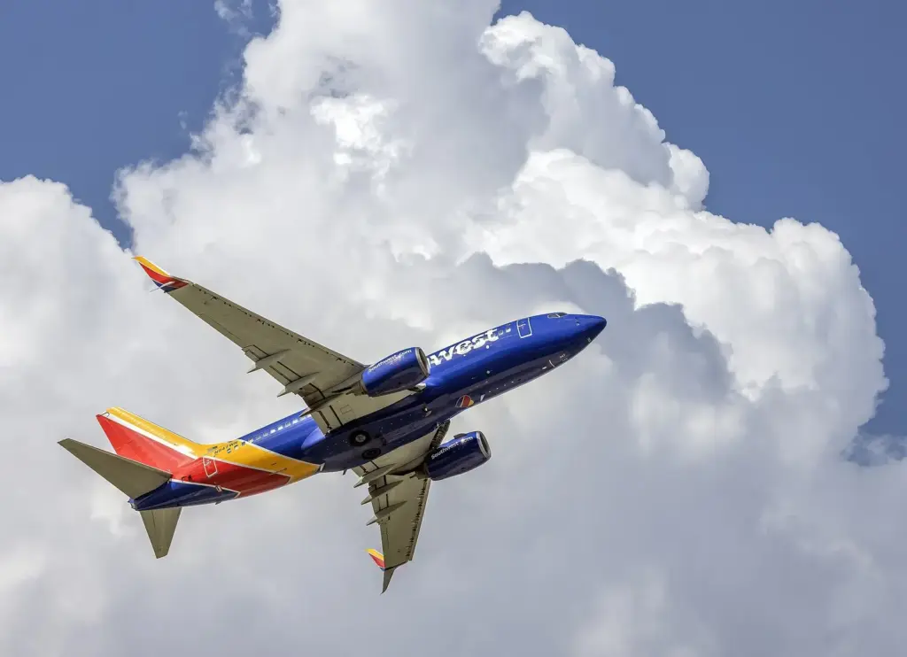 A Southwest Airlines Boeing 737 climbing out of BWI Marshall Airport under summer clouds