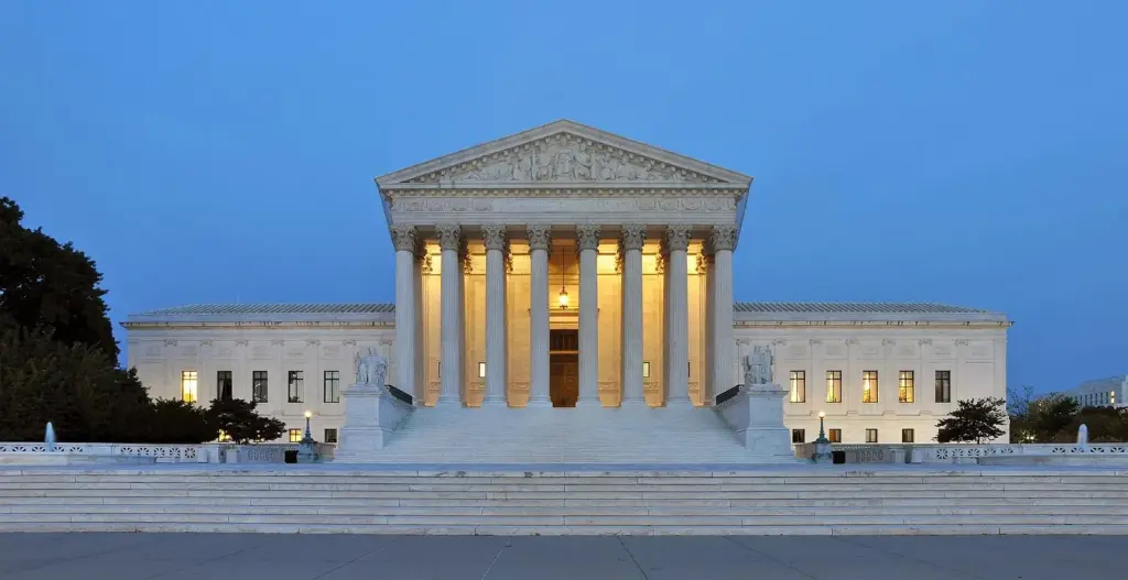 The marble Supreme Court Building with its columned portico lit at dusk