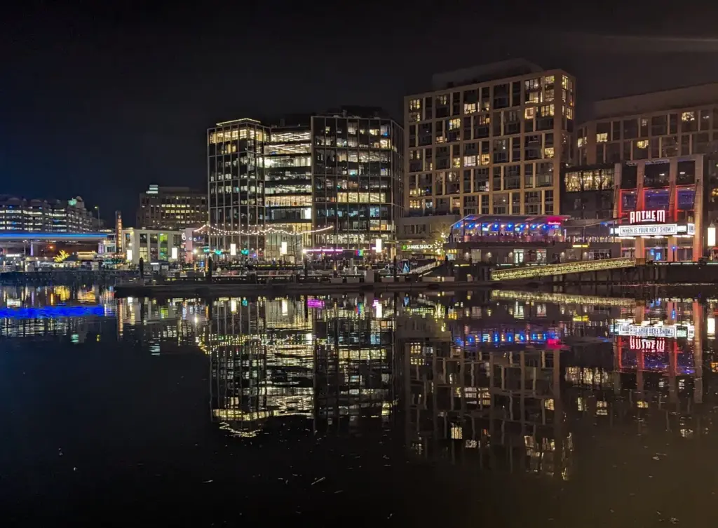 Lit restaurants and apartment buildings at the Wharf reflected in the dark water of the Washington Channel