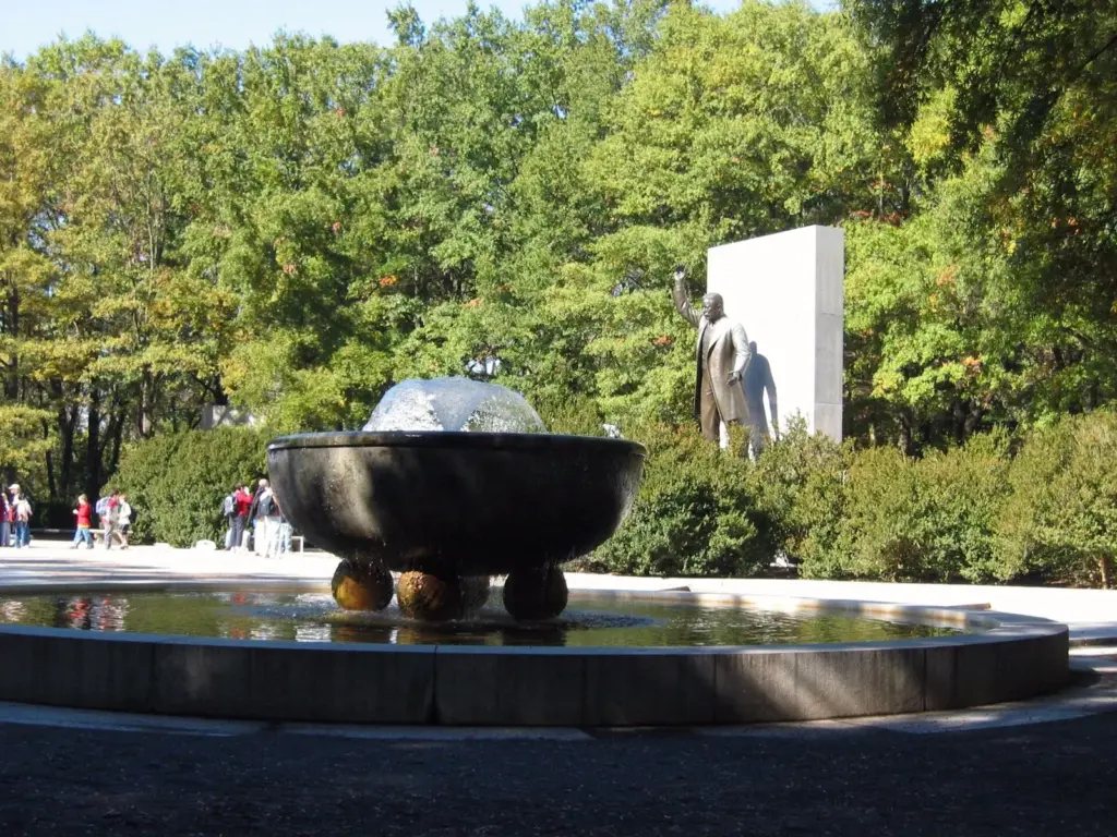 The memorial plaza on Theodore Roosevelt Island with a fountain basin and the bronze statue of Roosevelt among trees