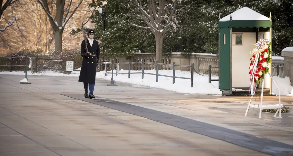 A sentinel of the 3rd U.S. Infantry Regiment standing at the Tomb of the Unknown Soldier after a snowfall, with a wreath and sentry box behind him