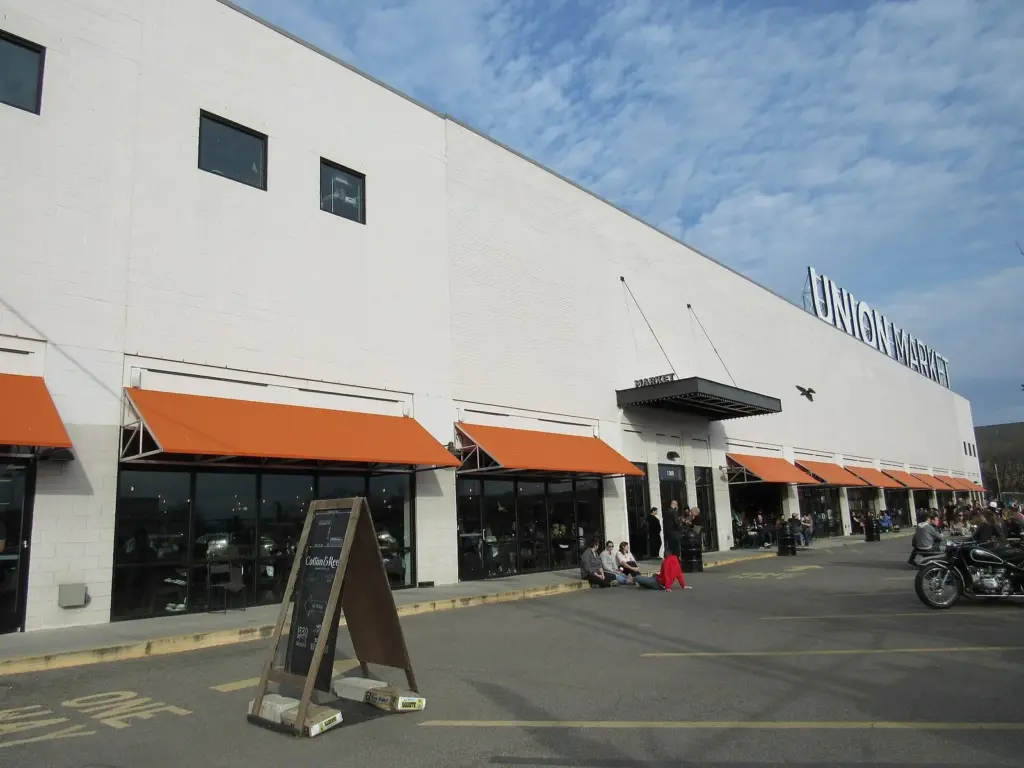 The long white market hall of Union Market with orange awnings and outdoor seating