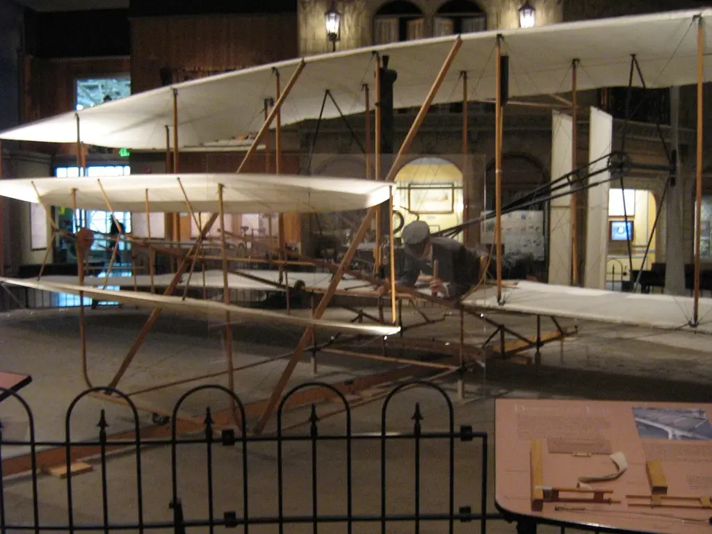 The 1903 Wright Flyer, a fabric-covered biplane, displayed at floor level behind a low railing
