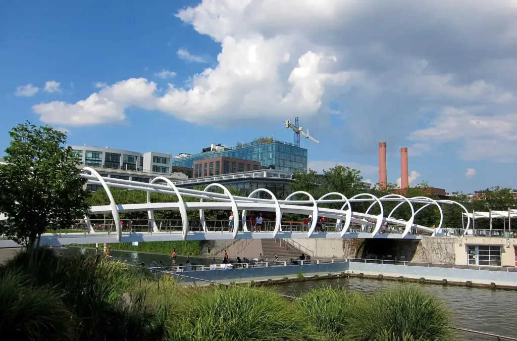 A white arched pedestrian bridge over the water at Yards Park on the Anacostia riverfront